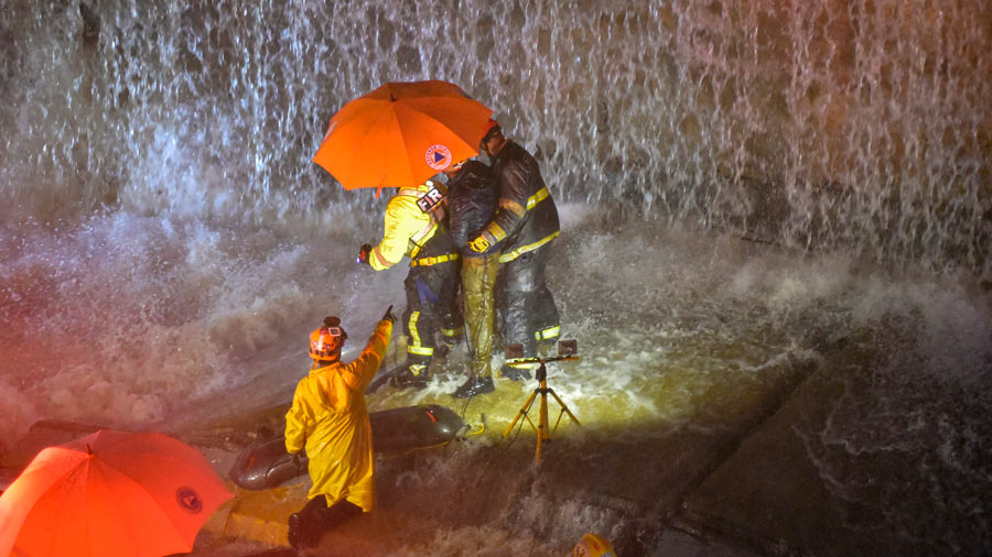 Rescatistas buscan personas atrapadas bajo un muro que colapsó sobre varios vehículos